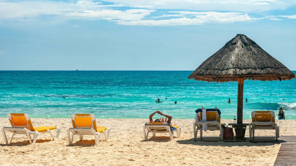 Relaxing on a beautiful Cancun beach, with golden sands and turquoise waters – an ideal spot for Cancun Summer Travel.