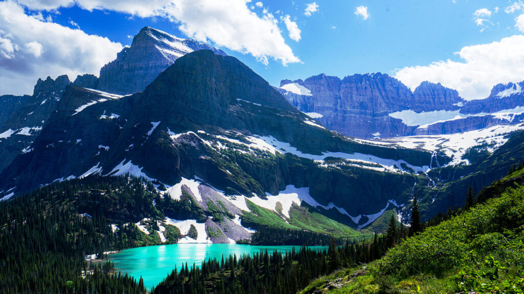 A pristine alpine lake surrounded by towering mountains in Glacier National Park, offering crystal-clear waters and lush forests.