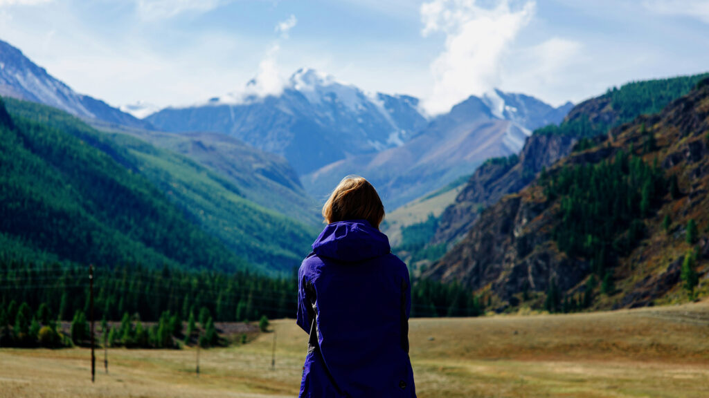 A hiker standing against a vast mountain range in the backcountry of Yellowstone National Park, taking in the natural wonder.