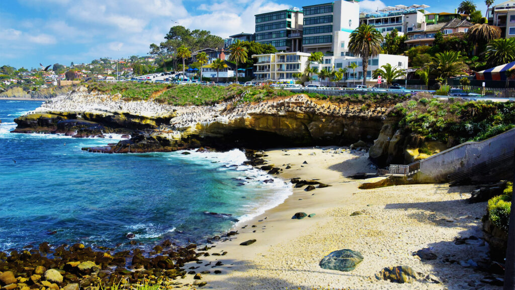 Scenic view of La Jolla Cove cliffs and sandy beach with ocean waves, a highlight among the best coastal cities in America