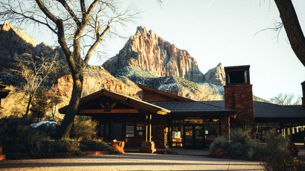 Visitor center lodge with red rock cliffs in the background near Zion, representing scenic hotels near U.S. National Parks.