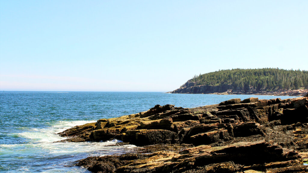 A coastal cliff with rugged rocks and the endless blue ocean stretching out, offering an off-the-beaten-path summer escape.