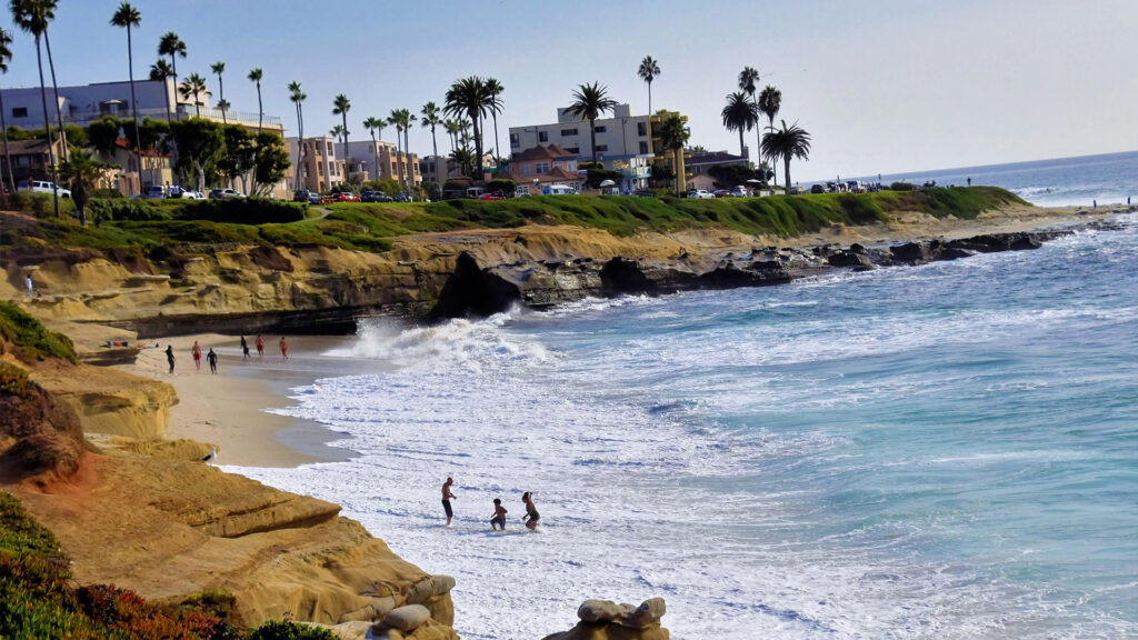Families enjoying waves along a scenic rocky beach coastline, capturing a classic San Diego family vacation moment