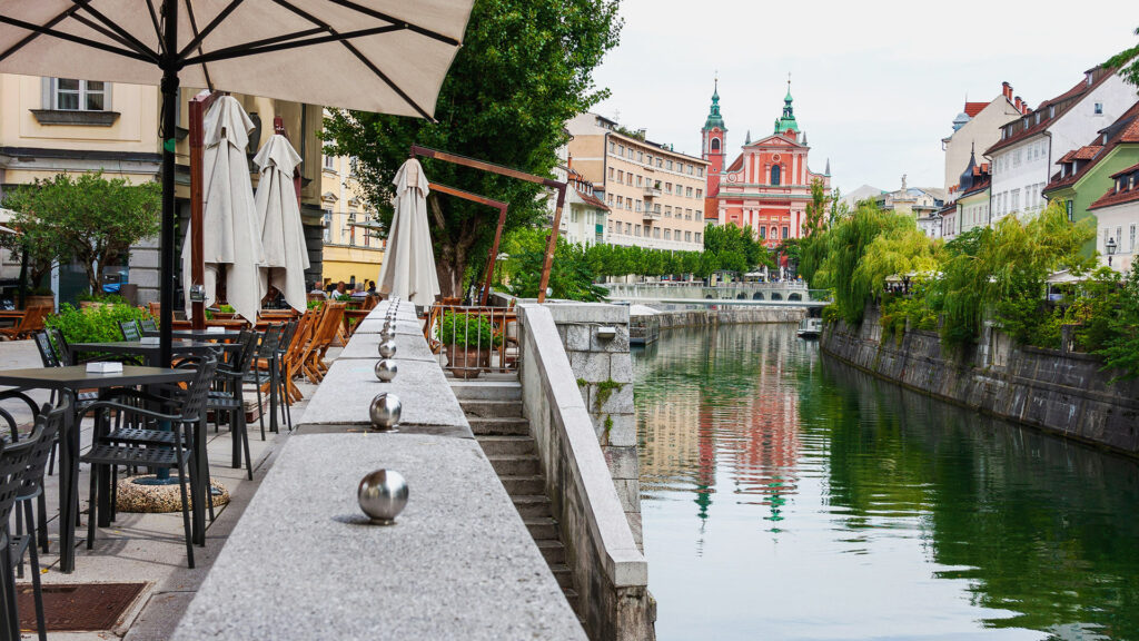 A peaceful riverside café scene with umbrellas, creating a relaxing atmosphere in a hidden summer gem.