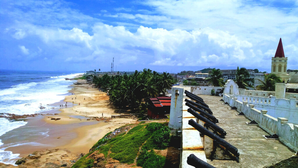 A sandy beach with historical architecture in the background, offering a mix of culture and natural beauty for an underrated summer vacation.