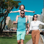 Family walking along a waterfront park with city skyline views, experiencing a vibrant San Diego family vacation
