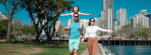 Family walking along a waterfront park with city skyline views, experiencing a vibrant San Diego family vacation