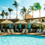 A relaxing pool area with tiki-style cabanas and palm trees at a resort in San Diego.