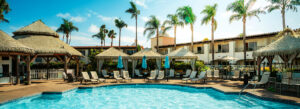 A relaxing pool area with tiki-style cabanas and palm trees at a resort in San Diego.
