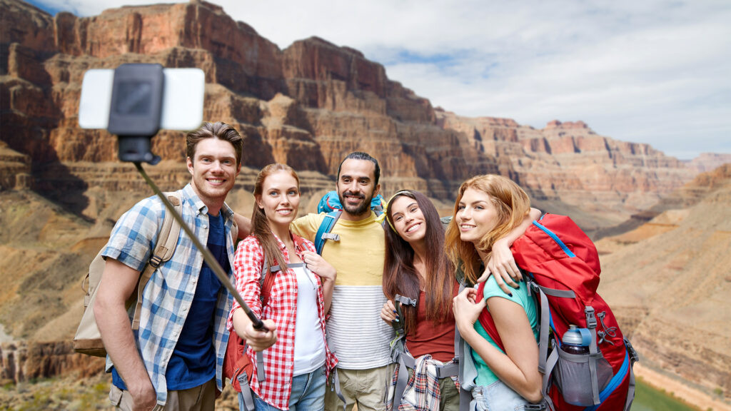 Group of friends taking a selfie on a hiking trip, embracing the rise of short trips to popular natural destinations.