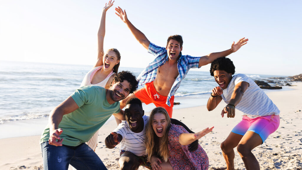 Group of young people enjoying the beach and sun, embodying the rise of short trips as a way to unwind and have fun.