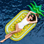 Woman relaxing on a pineapple-shaped float in the pool, embodying the popular summer travel trends of relaxation and fun.